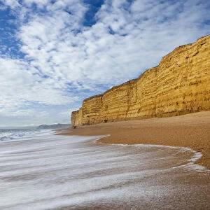 Waves wash clean Hive Beach backed by towering sandstone cliffs, Burton Bradstock