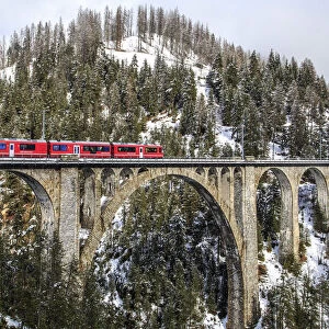 Wiesener Viaduct surrounded by snowy mountains and woods. Engadine. Canton of Graubunden