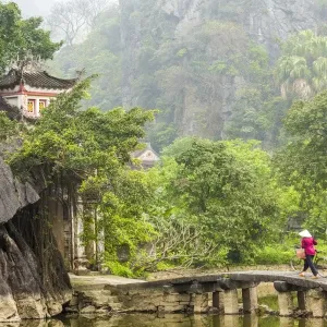 Woman crossing bridge with bicycle to temple, Tam Coc nr Ninh Binh, nr Hanoi, Vietnam Woman crossing bridge with bicycle to temple, Tam Coc nr Ninh Binh, nr Hanoi, Vietnam