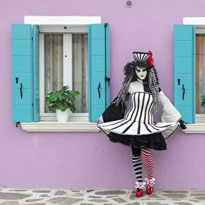 A woman poses in front of a colourful facade on Burano, Venice, Venato, Italy