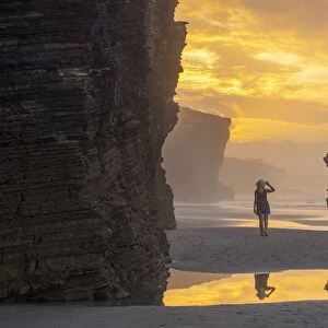 Woman walks at Playa de Las Catedrales at sunset, Ribadeo, Galicia, Spain, Iberian Peninsula (MR)