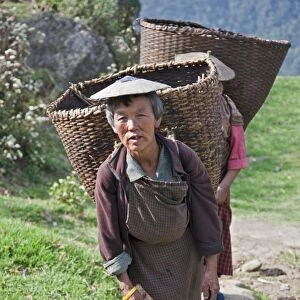 Women with large bamboo baskets go to collect produce from their hillside farms in the Mangde Chhu Valley