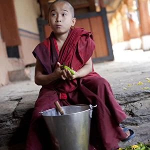 A young boy peeling vegetables in the dzong or monastery in Paro, Bhutan