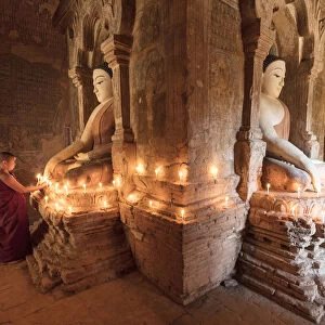 Young Buddhist monks pray in front of a statue of Buddha in a temple in Bagan, Myanmar