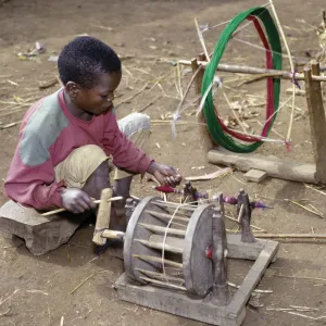 A young Dorze boy winds cotton onto a bobin for his father