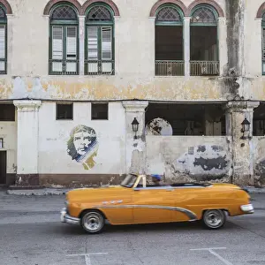 Che Guevara Prints: 50s Classic American car passing a mural of Che Guevara, Habana Vieja, Havana, Cuba