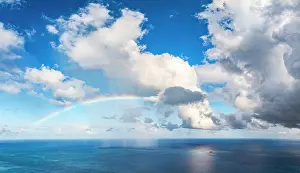 Leeward Islands Prints: Aerial panoramic of fluffy clouds and colorful rainbow in the sky during a thunderstorm