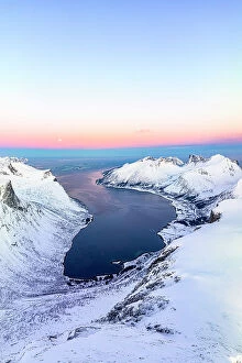 Images Dated 19th September 2023: Aerial panoramic of snowcapped mountains and coastal village of Bergsfjord at winter dawn, Senja