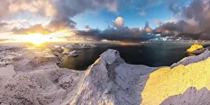 Finish Prints: Aerial panoramic of the snowy Haukland and Uttakleiv beach lit by sun rays at dawn