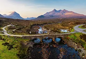 Model Released Prints: Aerial and panoramic view of a tourist on Sligachan Old Bridge observes Black Cuillin at sunrise