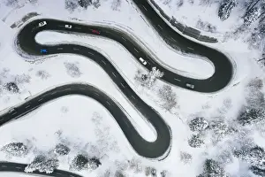 Earth From Above Prints: Aerial view of cars driving on narrow bends of mountain road in the snow