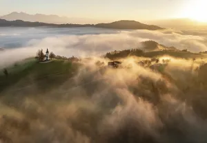 Above The Clouds Prints: Aerial view of the Church of St. Thomas in mist at dawn, in autumn, Skofja Loka, Slovenia