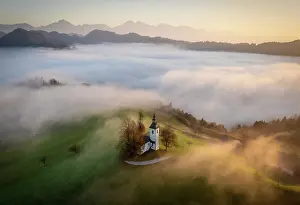 Above The Clouds Prints: Aerial view of the Church of St. Thomas in mist at dawn, in autumn, Skofja Loka, Slovenia
