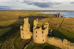 Aerial view of Dunstanburgh Castle on the Northumbrian coast, Embleton, Northumberland, England. Autumn (October) 2021