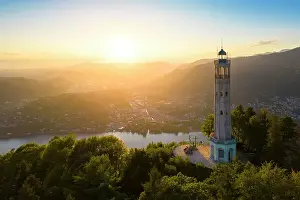 Como District Prints: Aerial view of the Faro Voltiano (Volta Lighthouse) of Brunate overlooking Como and Como Lake in summer at sunset