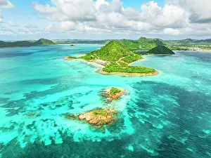 Leeward Islands Prints: Aerial view of lush green headland of Pearns Point overlooking a coral reef