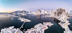 Lofoten Prints: Aerial view of snowcapped Reinebringen mountain overlooking Reine Bay and the cold arctic sea