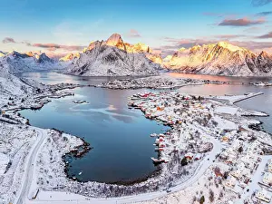 Lofoten Prints: Aerial view of the snowy fishing village of Reine with Olstind mountain on background