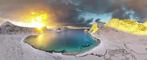 Finish Prints: Aerial view of the snowy Haukland beach and turquoise water of a fjord under a burning sky at dawn