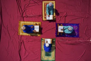 Pattern Prints: Aerial view of four student reading the koran in circle sitting on colourful carpet in