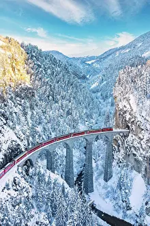 Railway Track Prints: Aerial view of train traveling on Landwasser viaduct across the snowy frozen woods