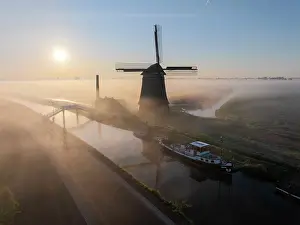 Moody Light Prints: An aerial view of a windmill in the mist at dawn, North Holland, Netherlands