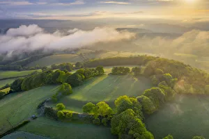 Aerial vista of Cadbury Castle Iron Age Hillfort in early morning sunlight, Devon Aerial vista of Cadbury Castle Iron Age Hillfort in early morning sunlight, Devon