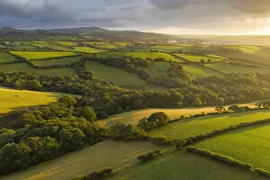 Aerial vista over farmland in evening sunshine, Devon, England. Summer (August) 2019