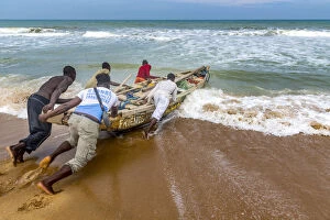 Africa, Benin, Grand Popo. A group of fishermen taking their boat into the water