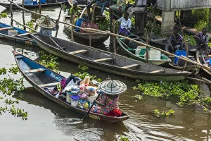 Africa, Benin, Lake NokouAA. A woman drives her canoe to the market in the famous