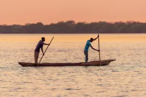 Africa, Botswana, Chobe River. Two Fishermen with traditional mokoro canoe on the river at sunset