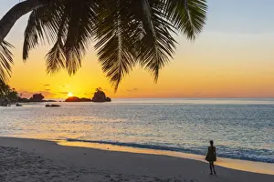 Africa, Seychelles, Mahe. Sunset at Anse Soleil Beach with a woman admiring the moment
