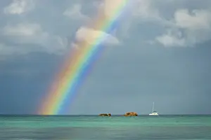 Rain Prints: Africa, Seychelles, Praslin. A rainbow over the ocean seen from Anse Volbert