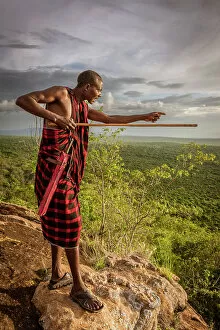 Images Dated 19th December 2022: Africa, Tanzania, Manyara Region. Msai man on a rock overlooking the landscape towards the plain