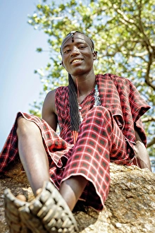 Clothing Prints: africa, Tanzania, Manyara Region. A handsome maasai warrior sitting on a rock