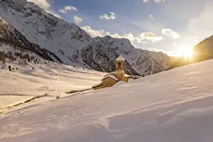 Alpine church of San Bernardo at sunset light in a mountain valley during winter season