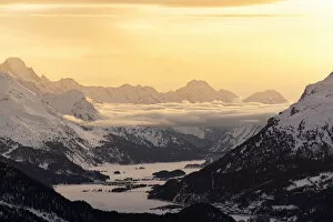 Images Dated 18th May 2021: Alpine lakes of Engadine and village of Maloja covered with snow at sunset