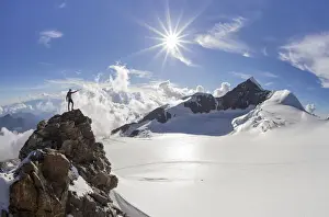 Ispiring Prints: Alpinist over a rock near Balmenhorn bivac looking to Lyskamm peak with sun in backlight
