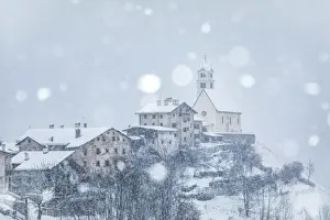 Rustic Prints: the ancient village of Colle Santa Lucia with the church on the hill under a snowfall