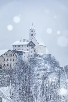 the ancient village of Colle Santa Lucia with the church on the hill under a snowfall