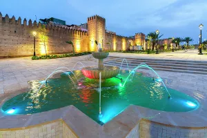 Fortified Wall Prints: Arabic marble fountain nearby the illuminated surrounding walls of medina, Fes, Morocco