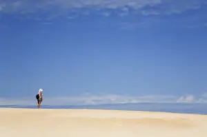 Australia, Tasmania, Strahan. A hiker looks out over Henty Dunes - a desert-like expanse of coastal sand dunes near
