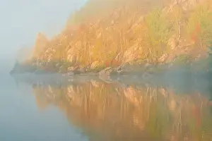 Autumn colors reflected in Lake Laurentian on an early foggy morning Sudbury, Ontario, Canada