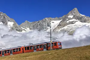 The Bahn train on its route with high peaks and mountain range in the background