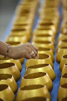 Bangkok, Thailand. A hand dropping a coin into an alms bowl on a altar in a buddhist