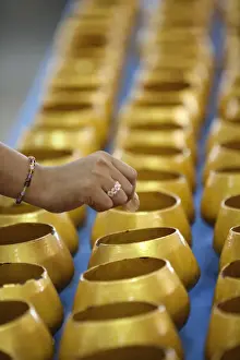 Bowl Prints: Bangkok, Thailand. A hand dropping a coin into an alms bowl on a altar in a buddhist
