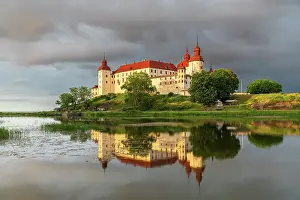 Fortified Wall Prints: Baroque Lacko castle and its reflection in the water of Vanem lake at sunset
