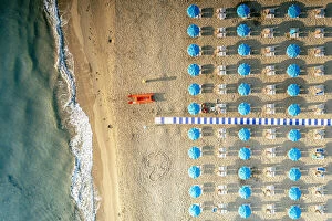 Empty Gallery: Beach umbrellas on sand washed by waves of turquoise sea from above, Vieste