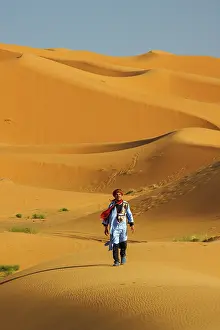 Sahara Prints: Berber man walking in the Erg Chebbi sand dunes, Sahara Desert, Merzouga, Morocco