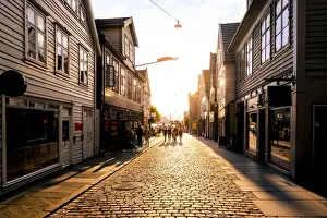 Timber Frame Prints: Bergen, Hordaland, Norway. Tourists walking in the old town at sunset
